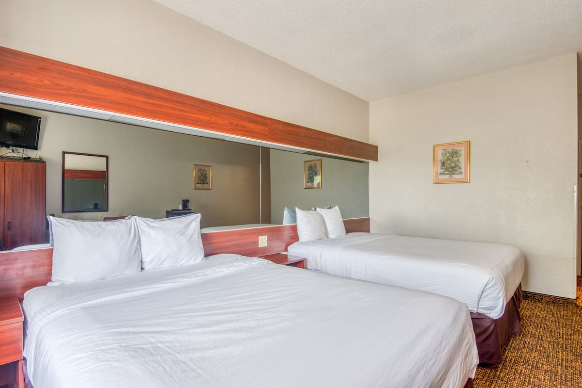 Quarto de hotel com duas camas, cabeceira de madeira, televisão de tela plana e um espelho.