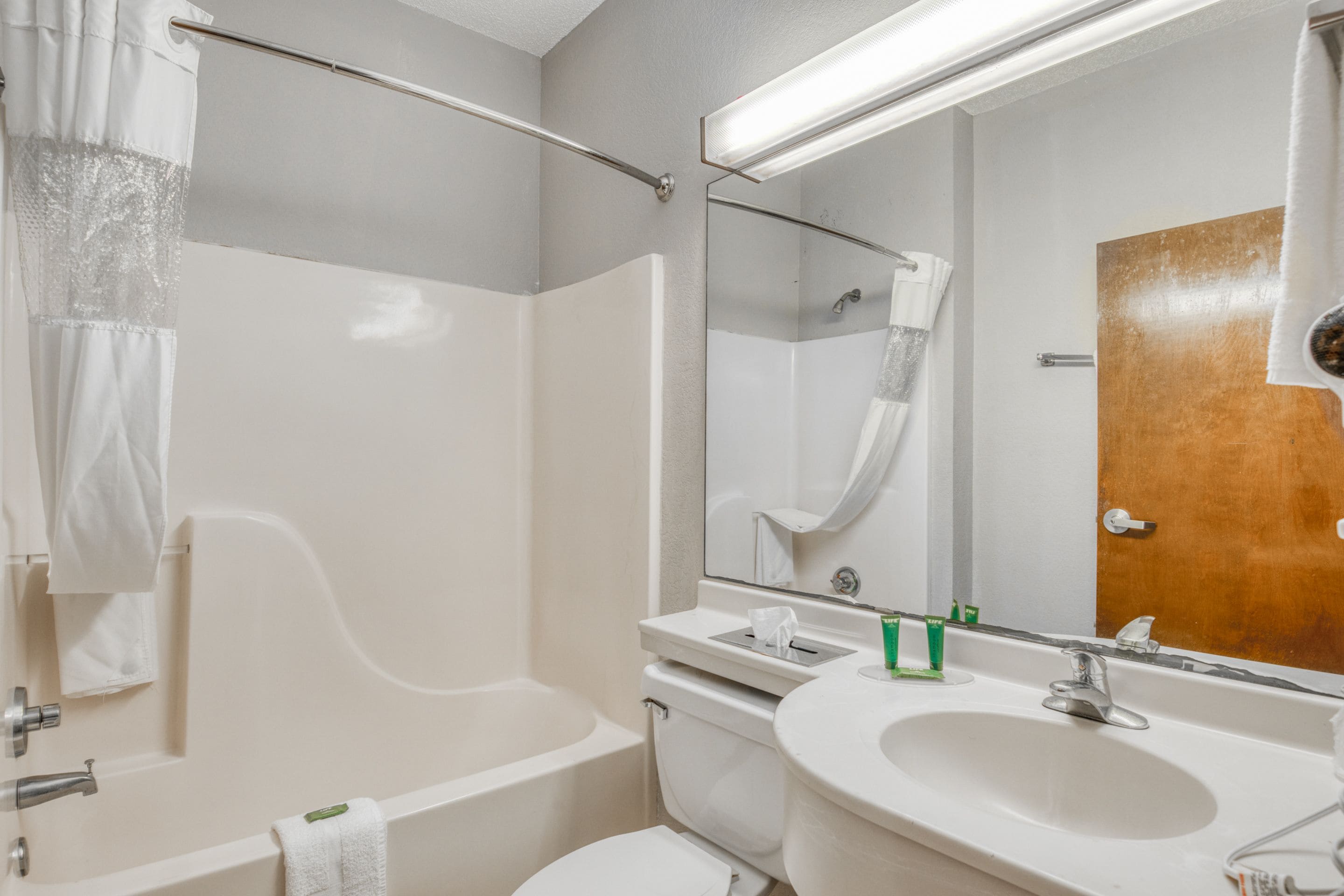 A modern bathroom with a bathtub, toilet, sink, and a large mirror.