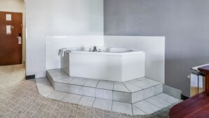 A modern bathroom with a freestanding bathtub, tiled floor, and a wooden door.
