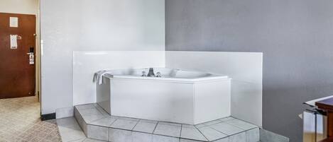 Un baño moderno con una bañera independiente, suelo de baldosas y una puerta de madera.