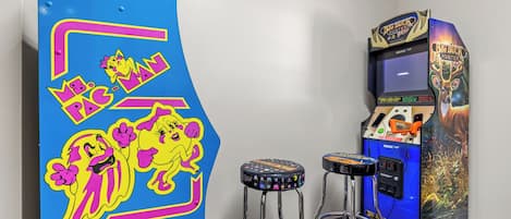 A room with a blue arcade machine featuring cartoon characters and two stools.