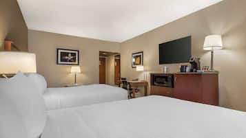Une chambre d’hôtel avec deux lits, un bureau, une télévision, une machine à café et une lampe.