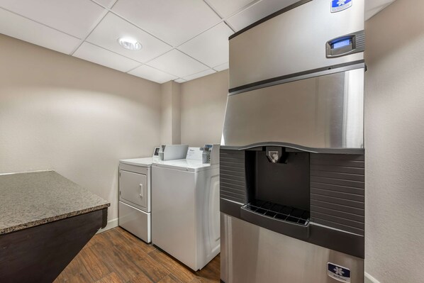 A compact kitchen with a stainless steel refrigerator, a built-in washing machine, and a granite countertop. - Best Western Plus Peak Vista Inn & Suites (Colorado Springs)