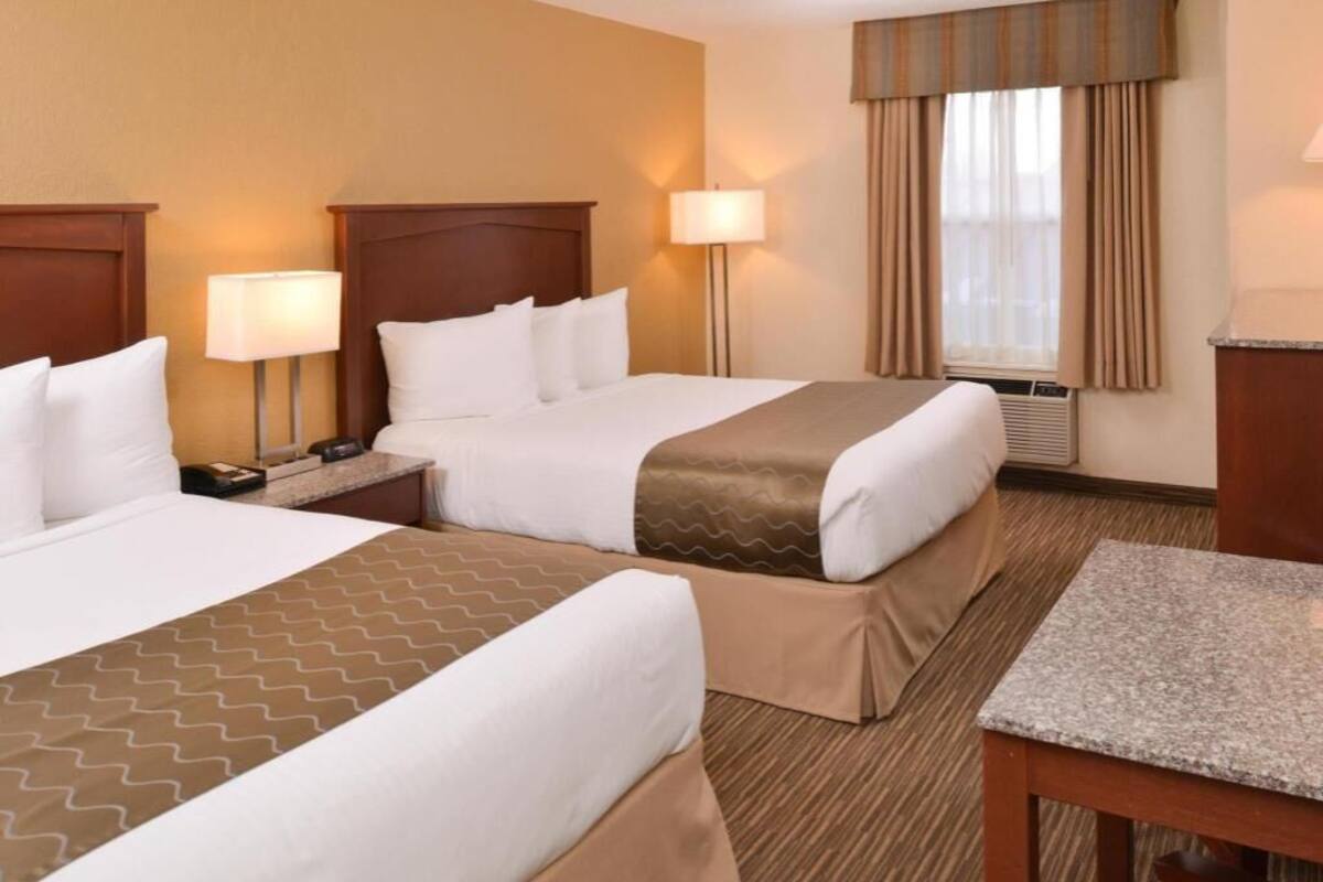 A hotel room with two beds, a desk, and a chair.