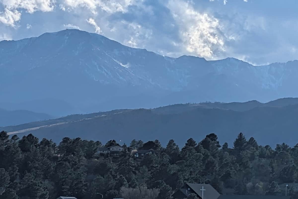A mountainous landscape with a house surrounded by dense forest.
