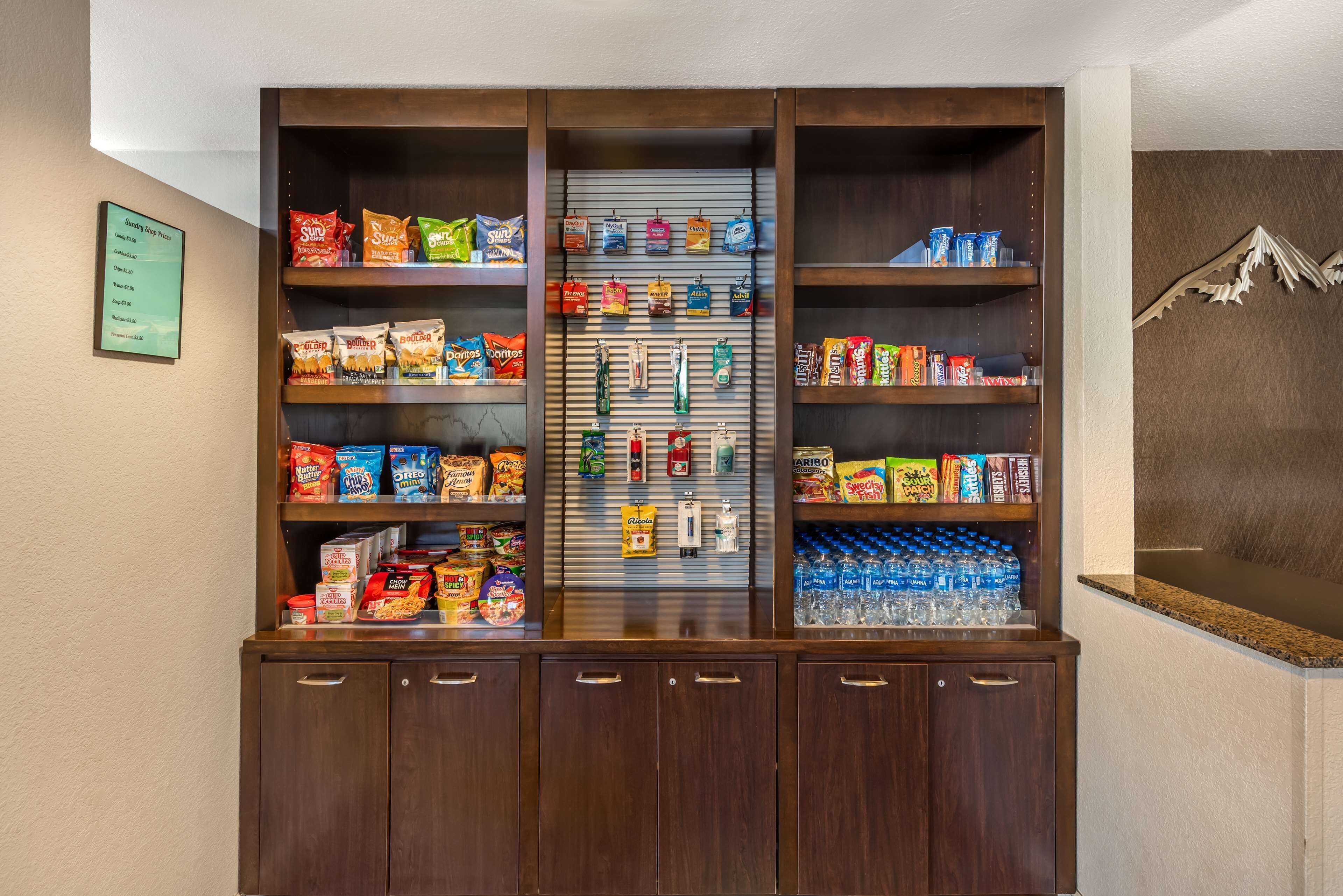 Een kiosk met snacks en drankjes, diverse verpakte producten, waterflesjes en een koffieapparaat.