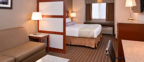 A hotel room with a bed, a sofa, a desk, and a TV.