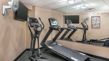 A gym with treadmills, a wall-mounted TV, and a poster.