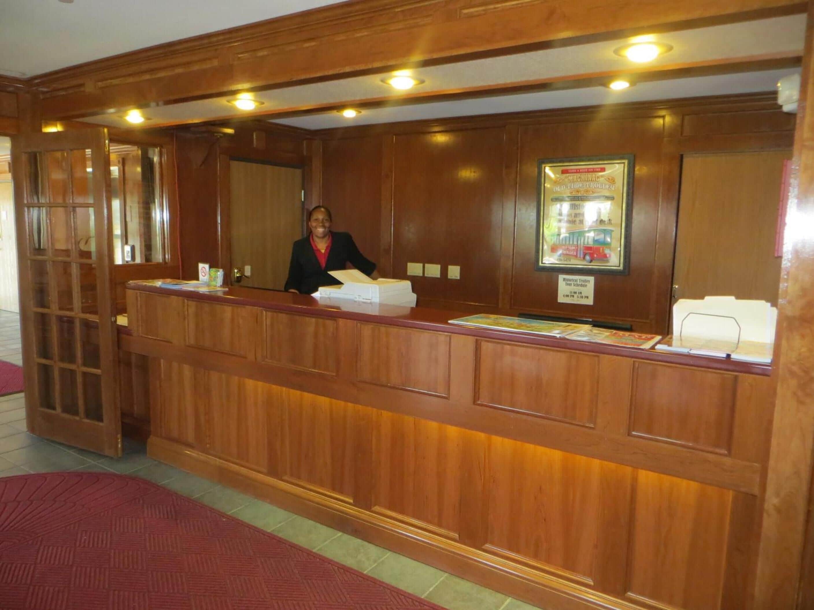 A reception desk with a wooden finish, a framed picture on the wall, and a sign indicating a historical exhibit.