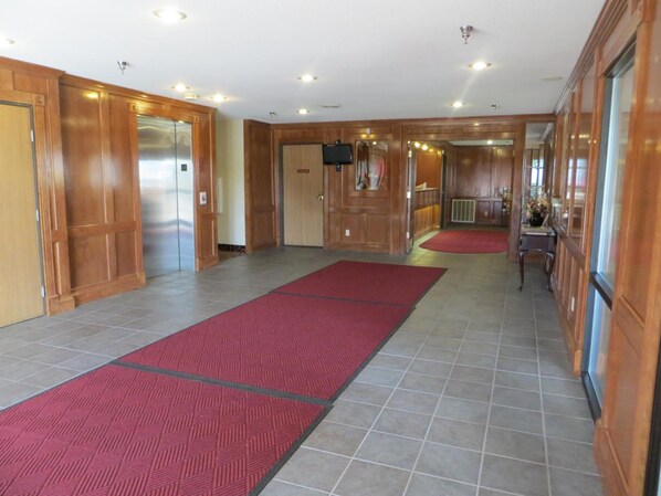 Un pasillo de hotel con paneles de madera, alfombra roja y suelo de baldosas.