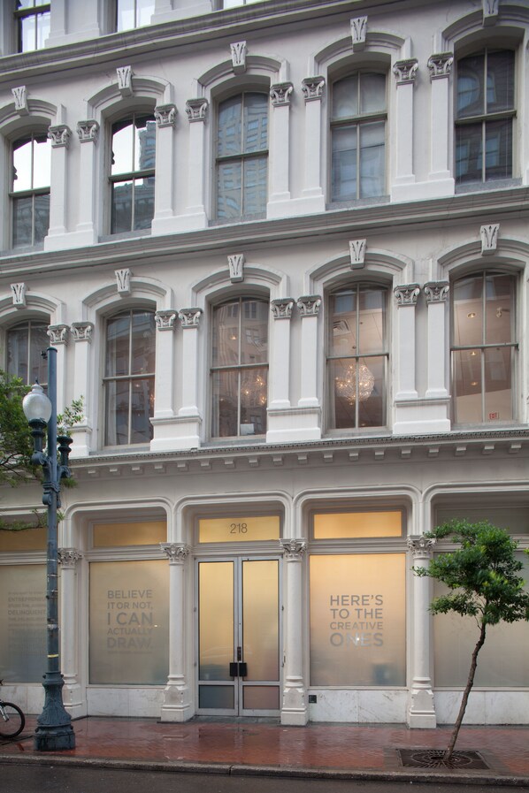 A building with large windows and a door with a sign that reads "HERE'S TO THE CREATIVE ONES".