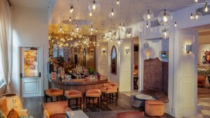 Uma área de bar com vários bancos, um balcão e luminárias pendentes.