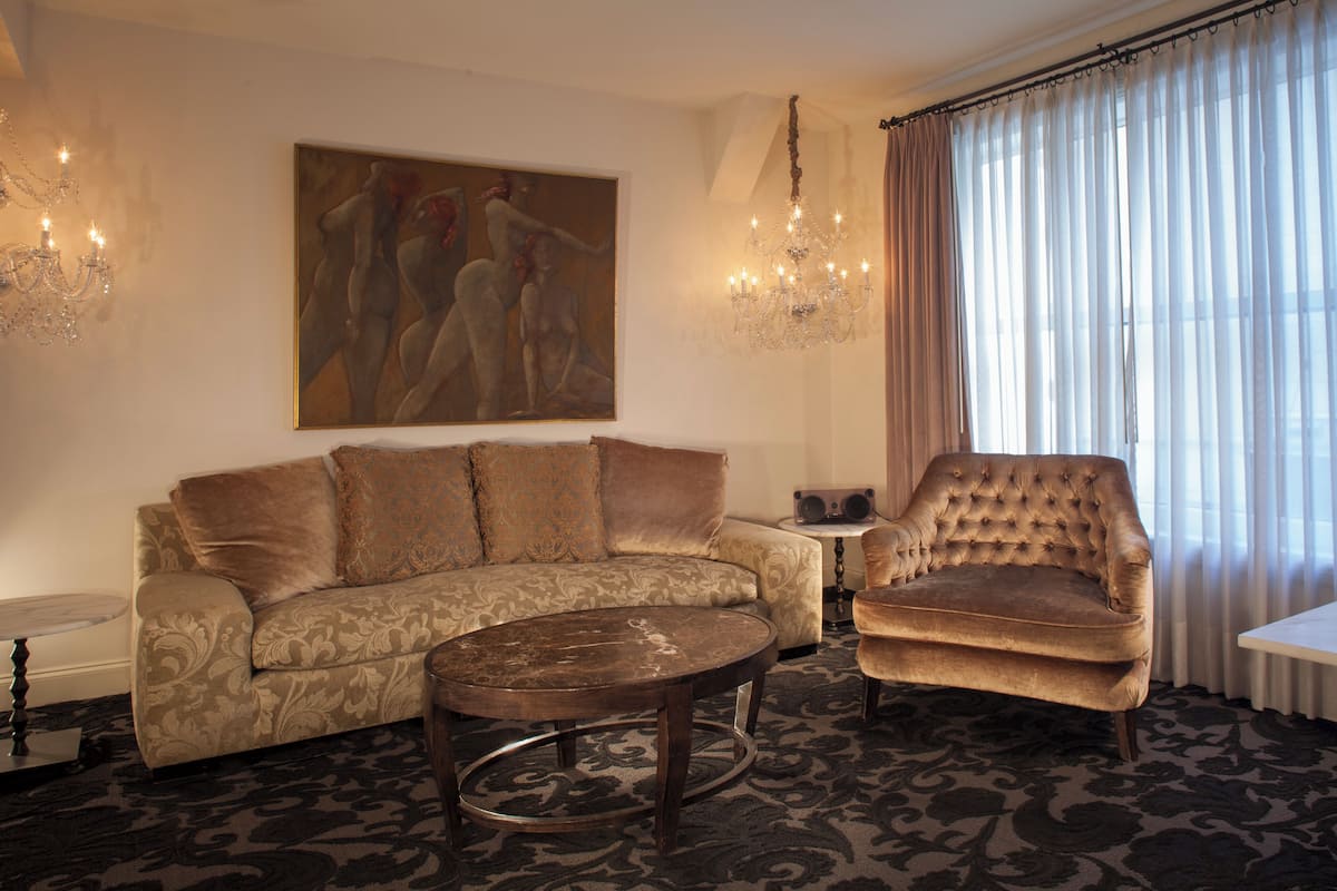 Un salon avec un canapé, un fauteuil, une table basse et un tableau accroché au mur.