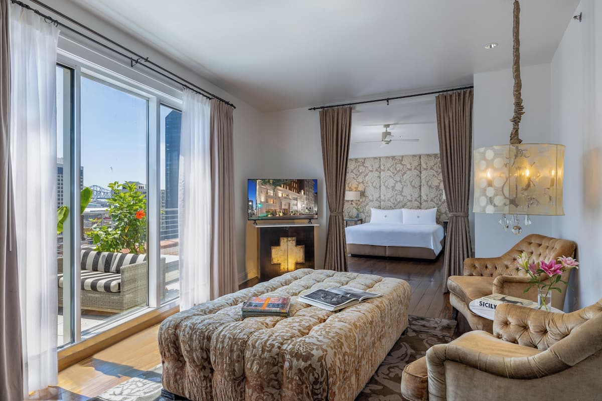 Une chambre d’hôtel avec un grand lit, un canapé, une télévision et une vue sur la ville.