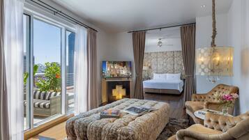 Une chambre d’hôtel avec un grand lit, un canapé, une télévision et une vue sur la ville.
