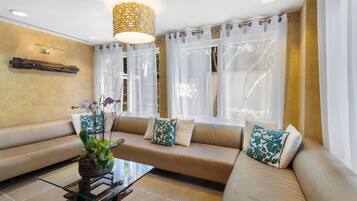 A modern living room with a beige sofa, a glass coffee table, and a potted plant.