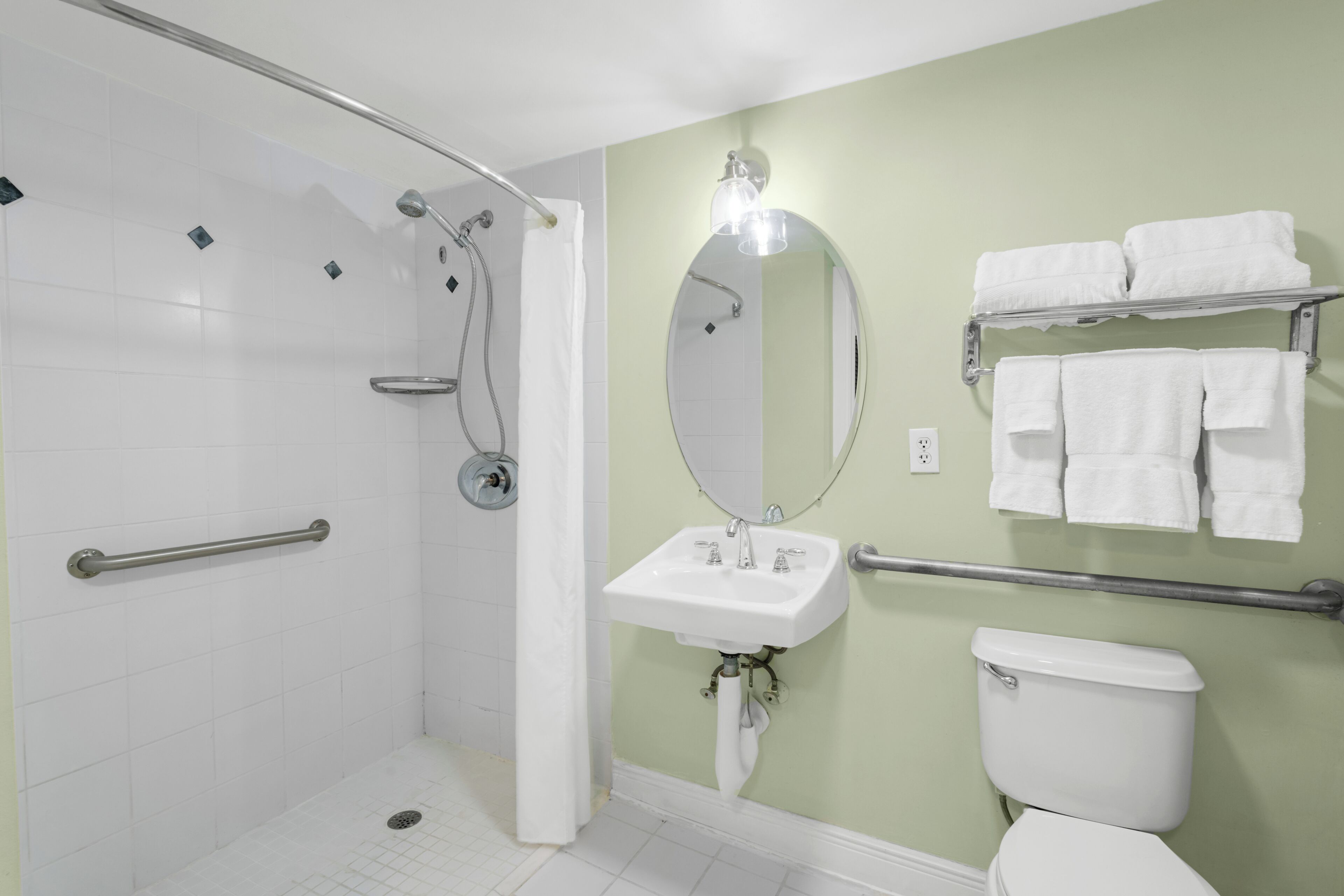 A bathroom with a shower, toilet, sink, and towel rack.