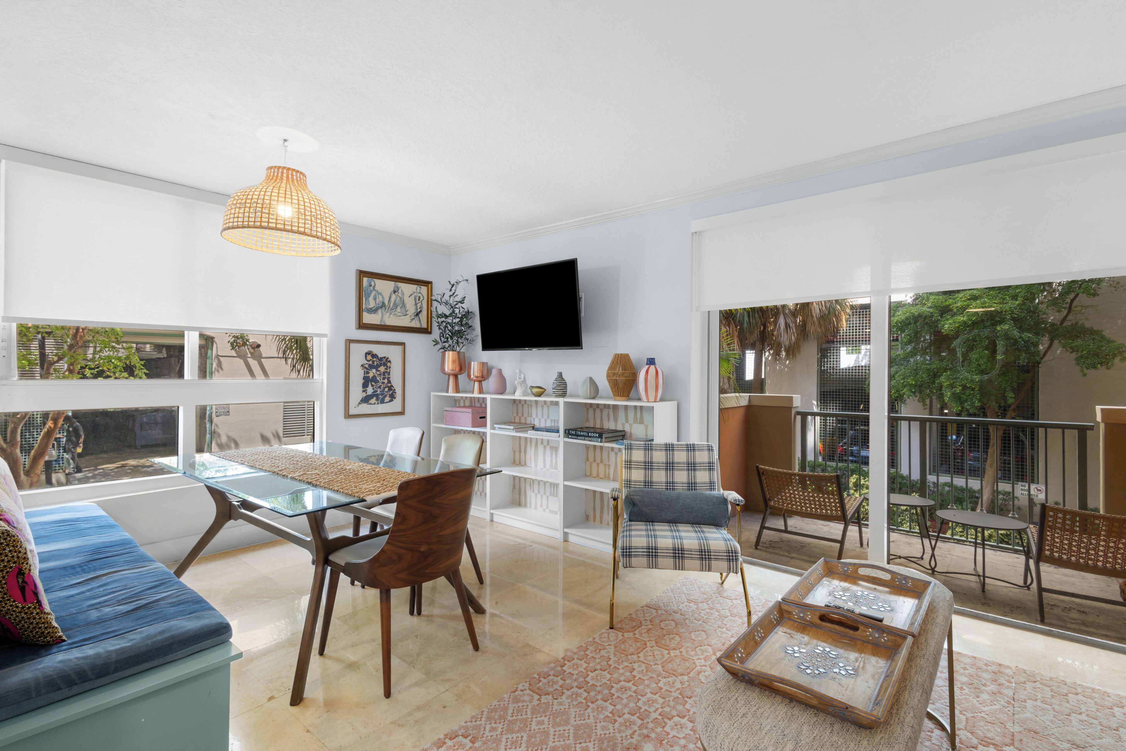 Een moderne woonkamer met een bank, stoelen, een televisie en een balkon met tuinmeubilair.