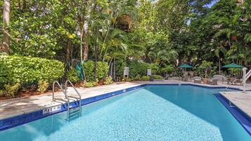 A swimming pool surrounded by lush greenery and outdoor furniture.