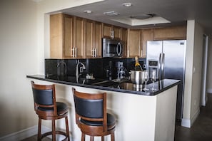 Una cucina moderna con mobili in legno, elettrodomestici in acciaio inossidabile e un'isola centrale con due sgabelli da bar.