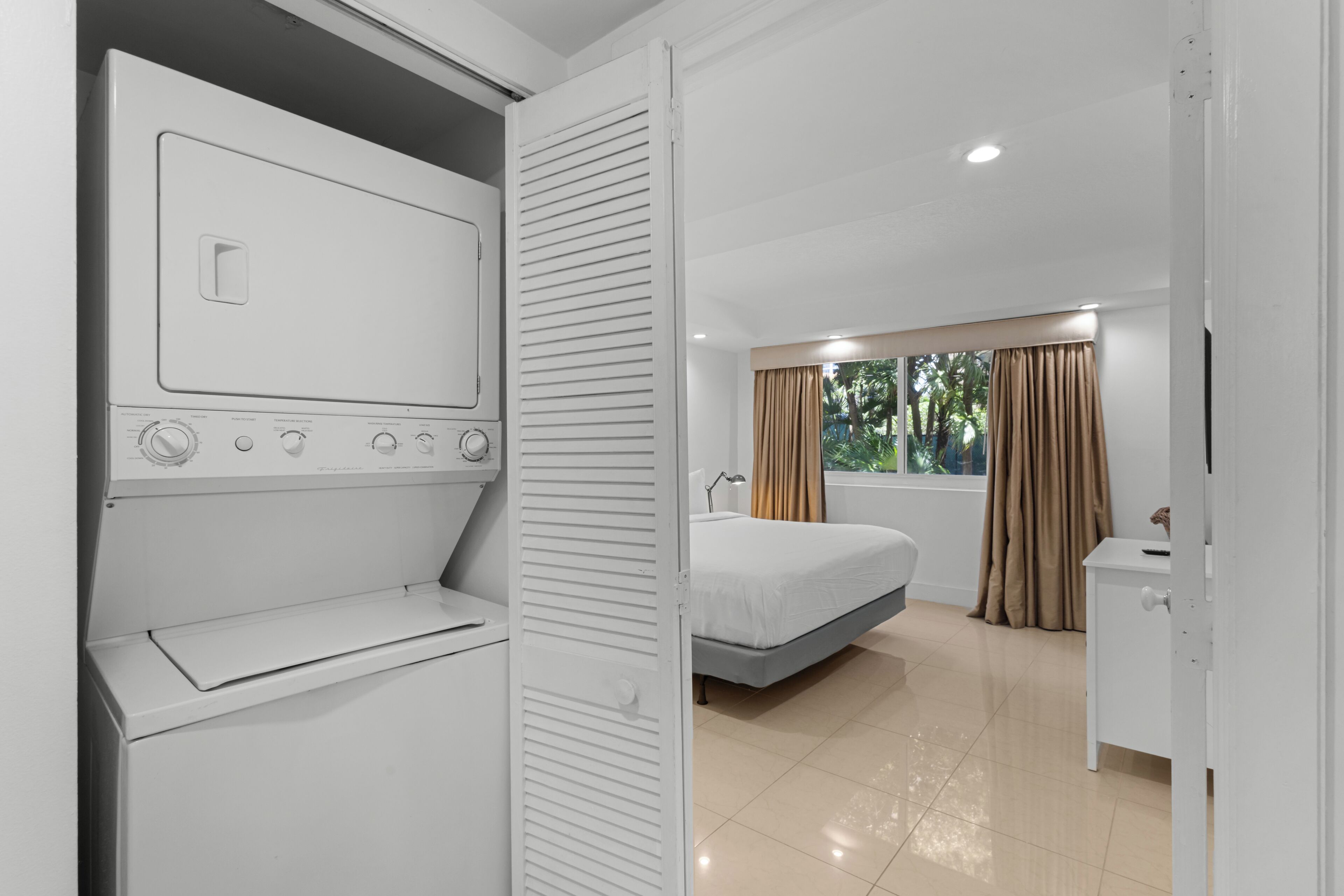 Een hotelkamer met een bed, een bureau, een kledingkast en een wasmachine.