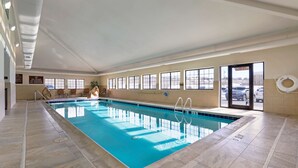 Une piscine intérieure à l’eau claire, avec des murs carrelés et des fenêtres.