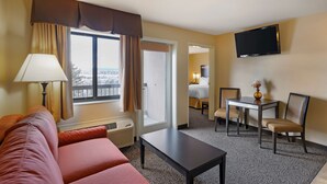 Une chambre d’hôtel équipée d’un canapé, d’une table, d’une télévision et offrant une vue sur l’extérieur.