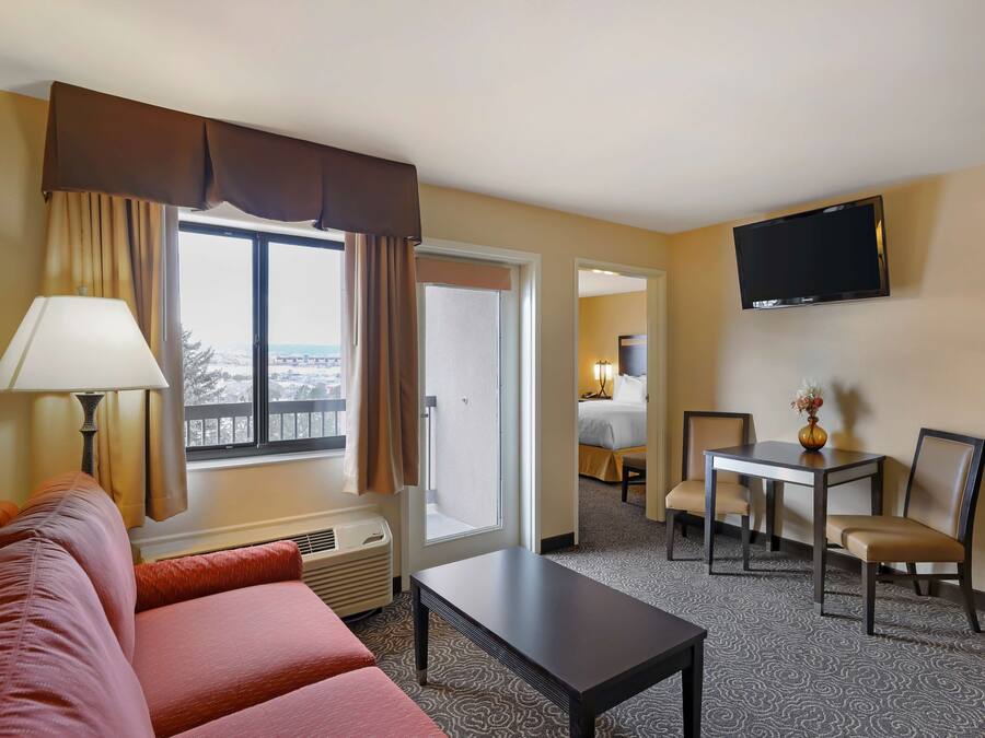 Una habitación de hotel con sofá, una mesa, televisor y vistas al exterior.