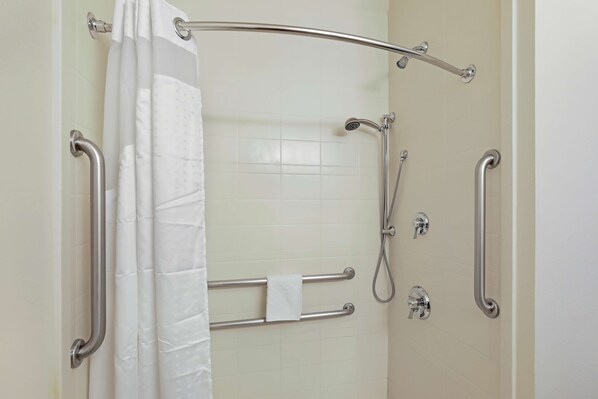 A shower area with a grab bar, a showerhead, and a towel rack.