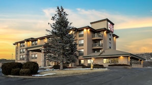 Un hôtel à plusieurs étages doté d’un parking, d’un sapin de Noël et d’une enseigne indiquant qu’il fait partie de la chaîne Best Western Plus.