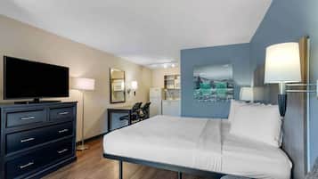 A hotel room with a bed, a flat-screen TV, a dresser, a desk, and a chair.