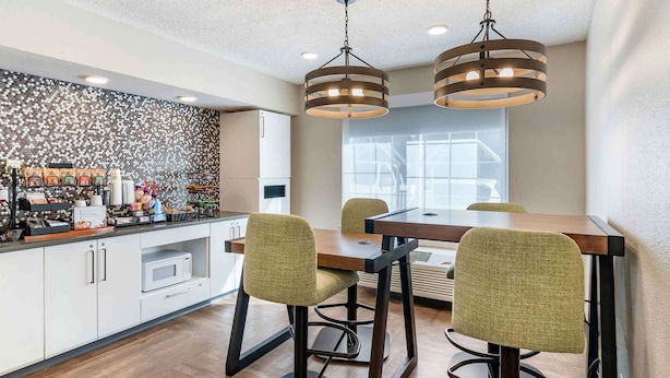 Una cocina moderna con un salpicadero decorativo, un comedor con una mesa de madera y sillas verdes, e iluminación colgante.