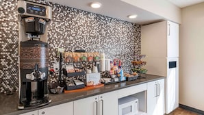 Una kitchenette con cafetera, cápsulas de café y microondas.