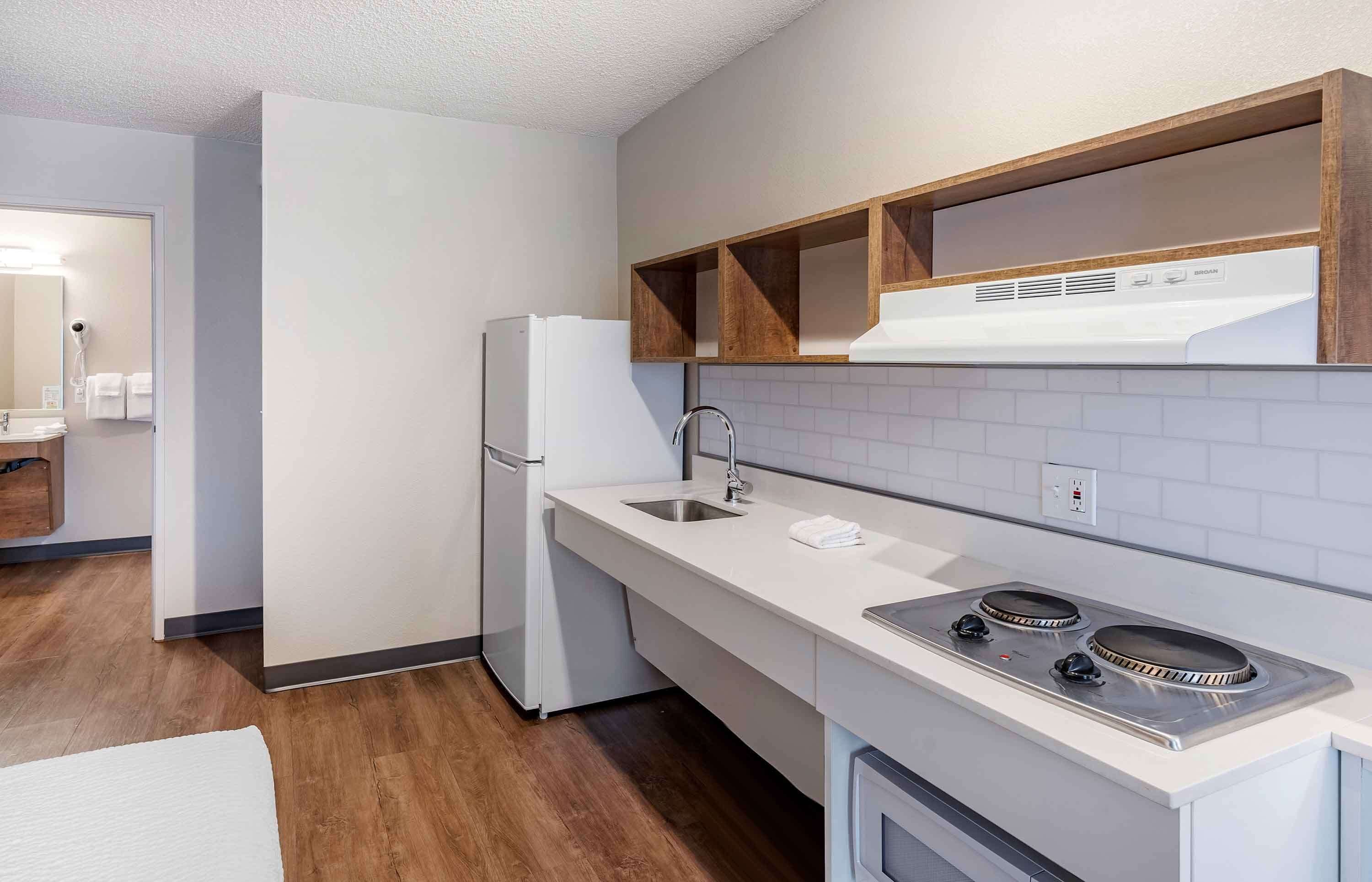 A modern kitchen with white cabinets, a stainless steel sink, and a built-in oven.