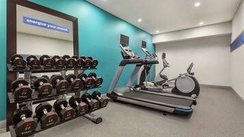 A gym with dumbbells, treadmills, and an elliptical machine.