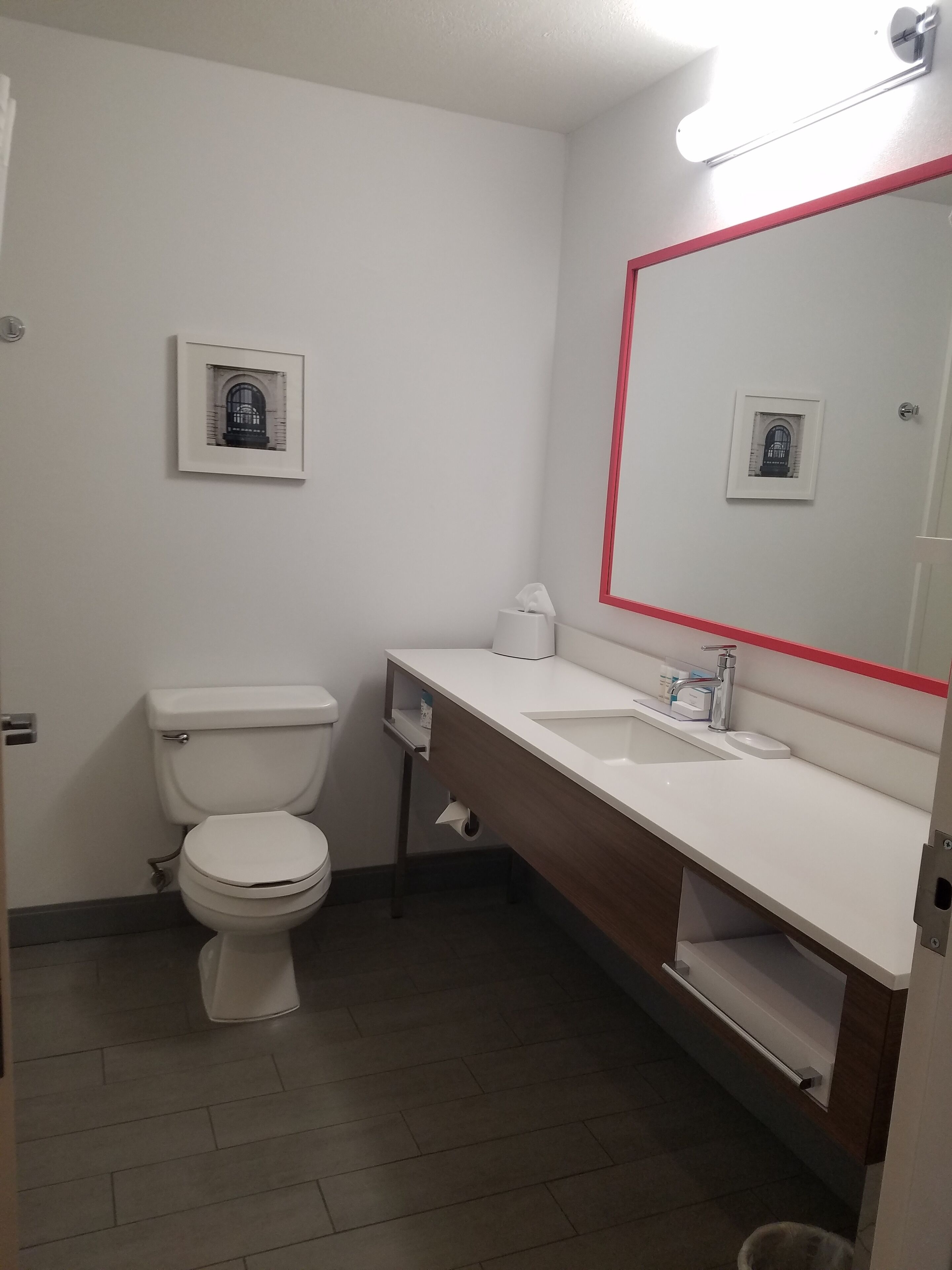 A small, clean bathroom with a toilet, sink, and mirror.