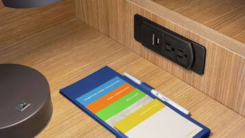 A notebook with a pen, a power outlet, and a charging station on a wooden surface.