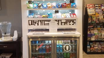 A snack display with a variety of snacks and drinks, a clock, and a sign indicating the price of snacks and drinks.