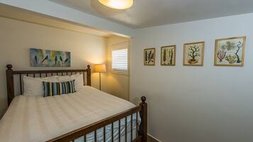 A bedroom with a wooden bed, a nightstand, a lamp, and wall art.