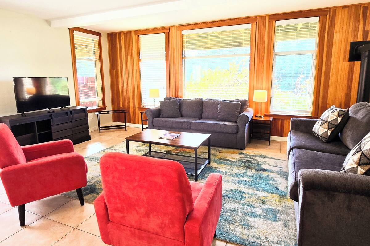 A living room with a sofa, two armchairs, a coffee table, a TV, and a lamp.