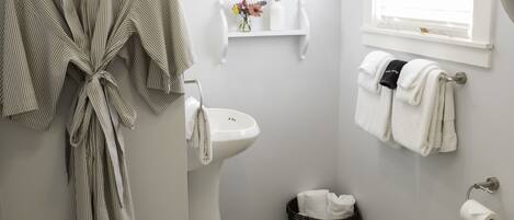 A bathroom with a toilet, sink, and a robe hanging on the wall.