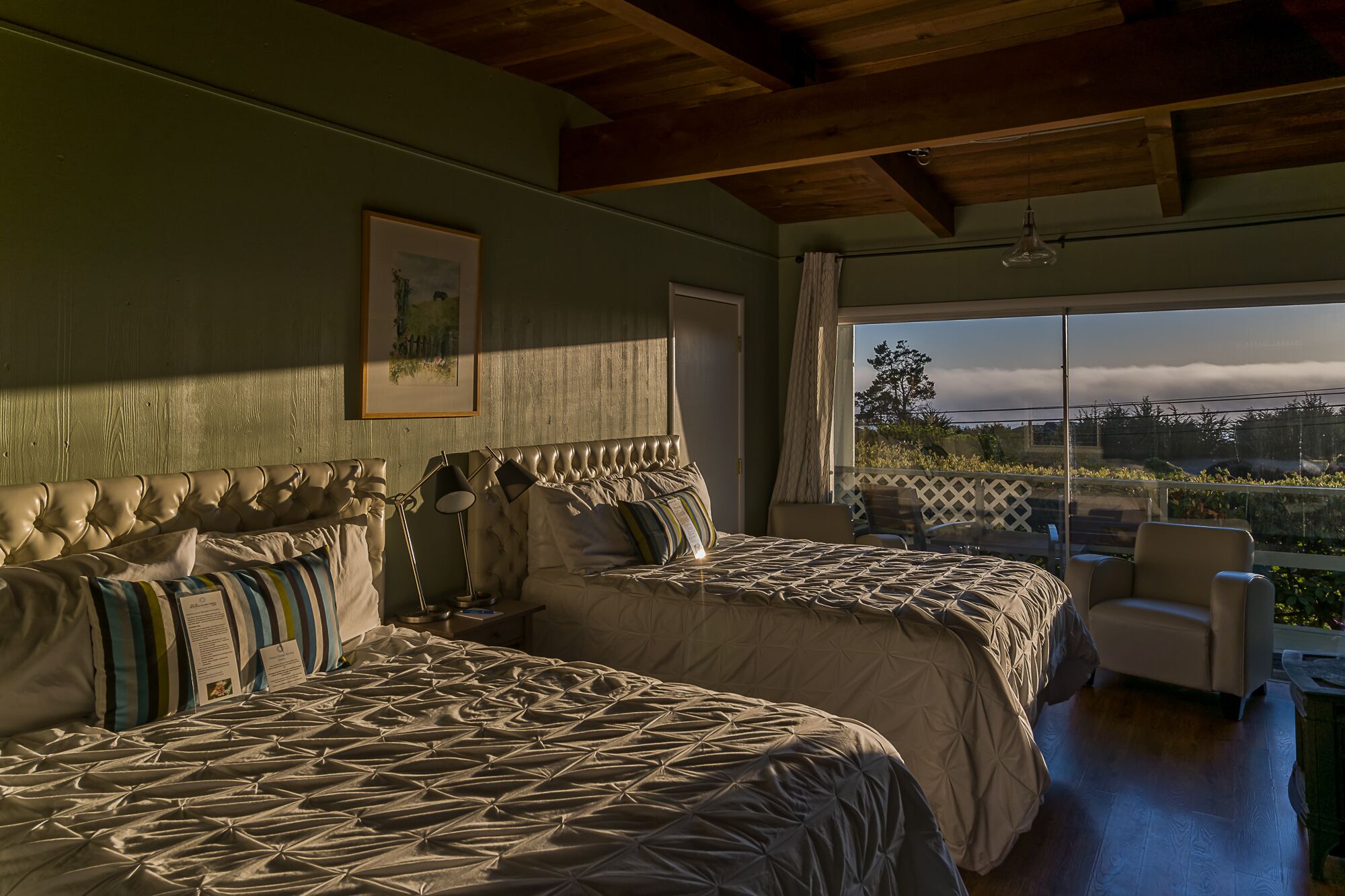 A bedroom with two beds, a large window, and a view of the outdoors.