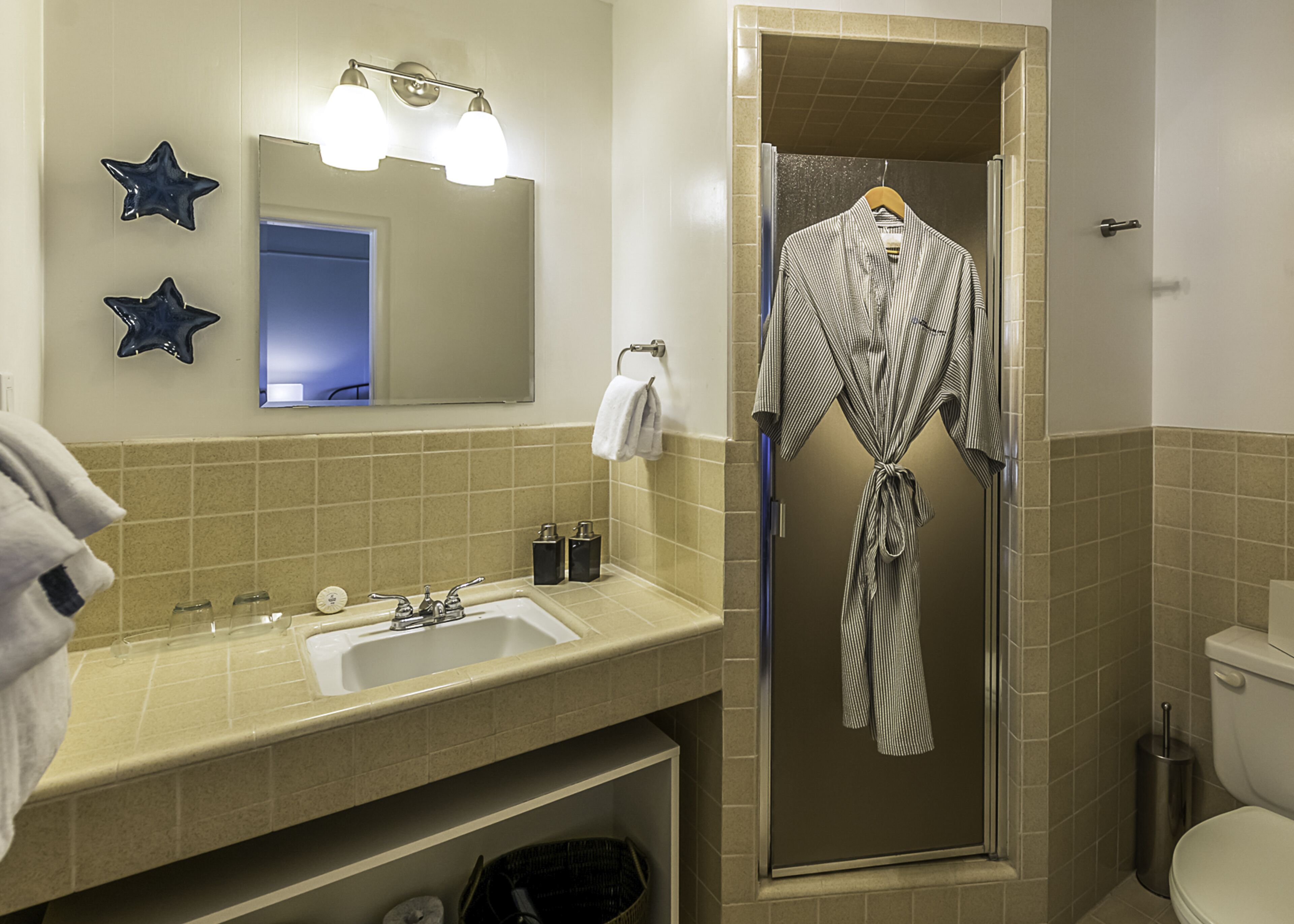 Ein Badezimmer mit Waschbecken, Spiegel, Sterndekorationen und einem Bademantel, der an der Tür hängt.