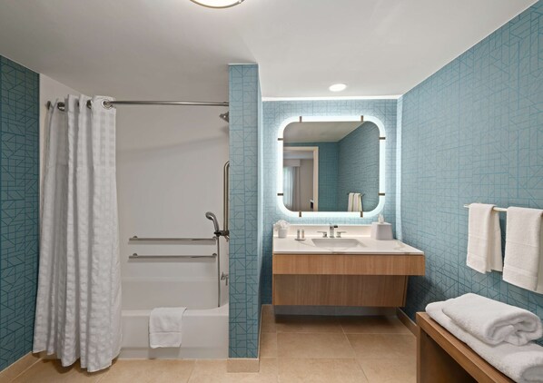 A bathroom with a bathtub, a shower, a sink, and a mirror.