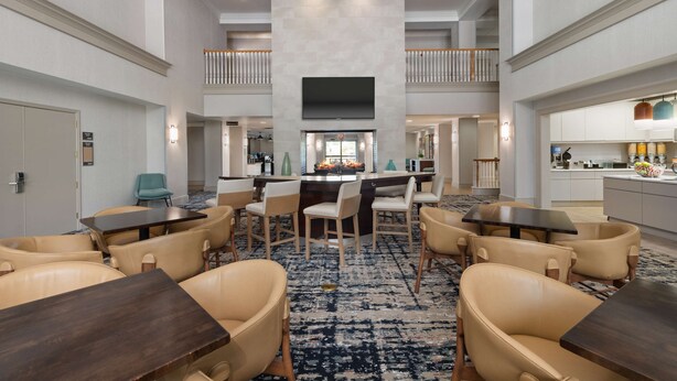 Eine geräumige Hotelhalle mit einer zentralen Sitzecke, einer Bar und einer Küche im Hintergrund.