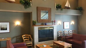 A cozy lounge area with a fireplace, seating, and decorative elements like plants and wall art. - Comfort Inn Port Huron (Port Huron)