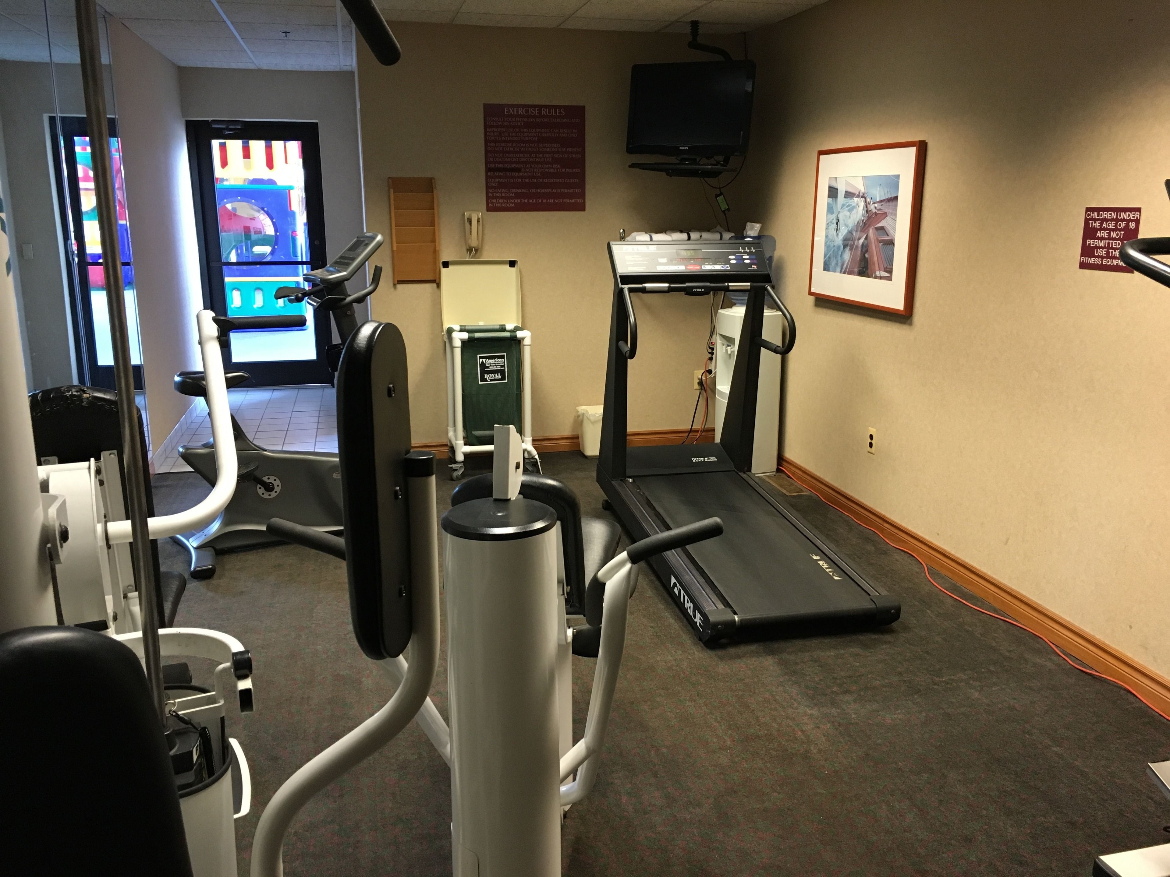 A gym with cardio machines, a treadmill, and a stationary bike.