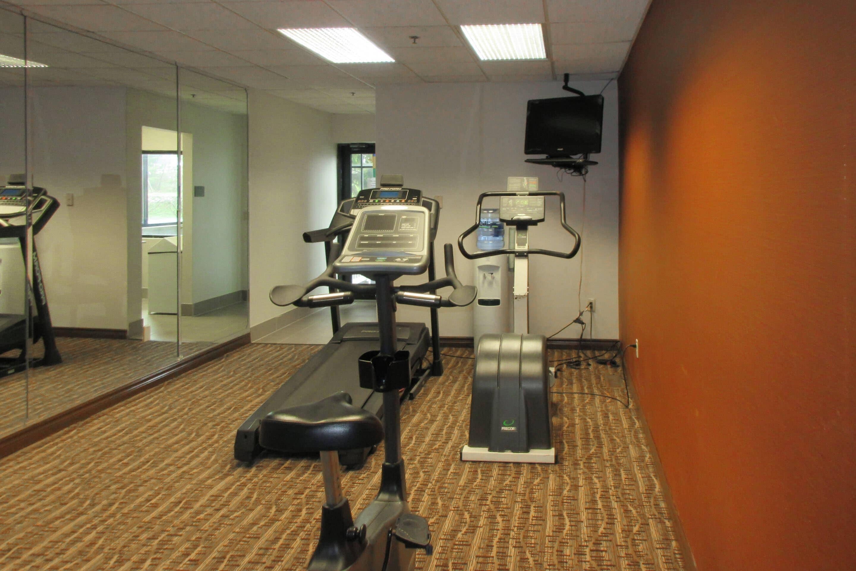A fitness room with treadmills, a stationary bike, and a mirrored wall.