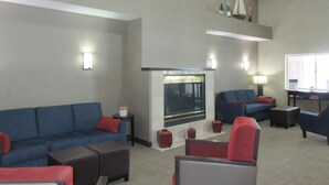 A spacious living area with a fireplace, sofas, and armchairs. - Comfort Inn Port Huron (Port Huron)