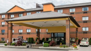 A multi-story hotel with a covered entrance, parking lot, and various potted plants. - Comfort Inn Port Huron (Port Huron)